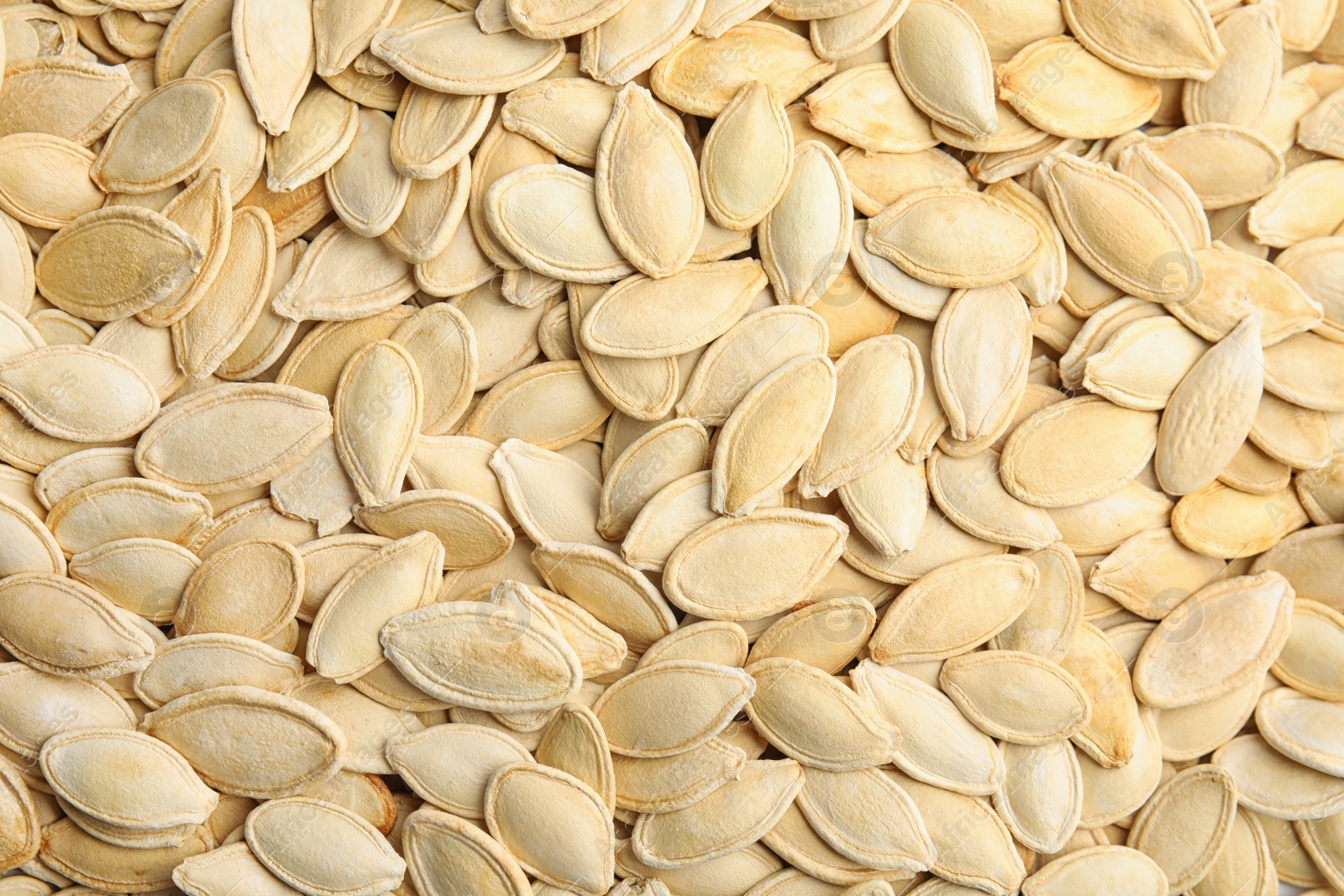 Photo of Raw unpeeled pumpkin seeds as background, top view