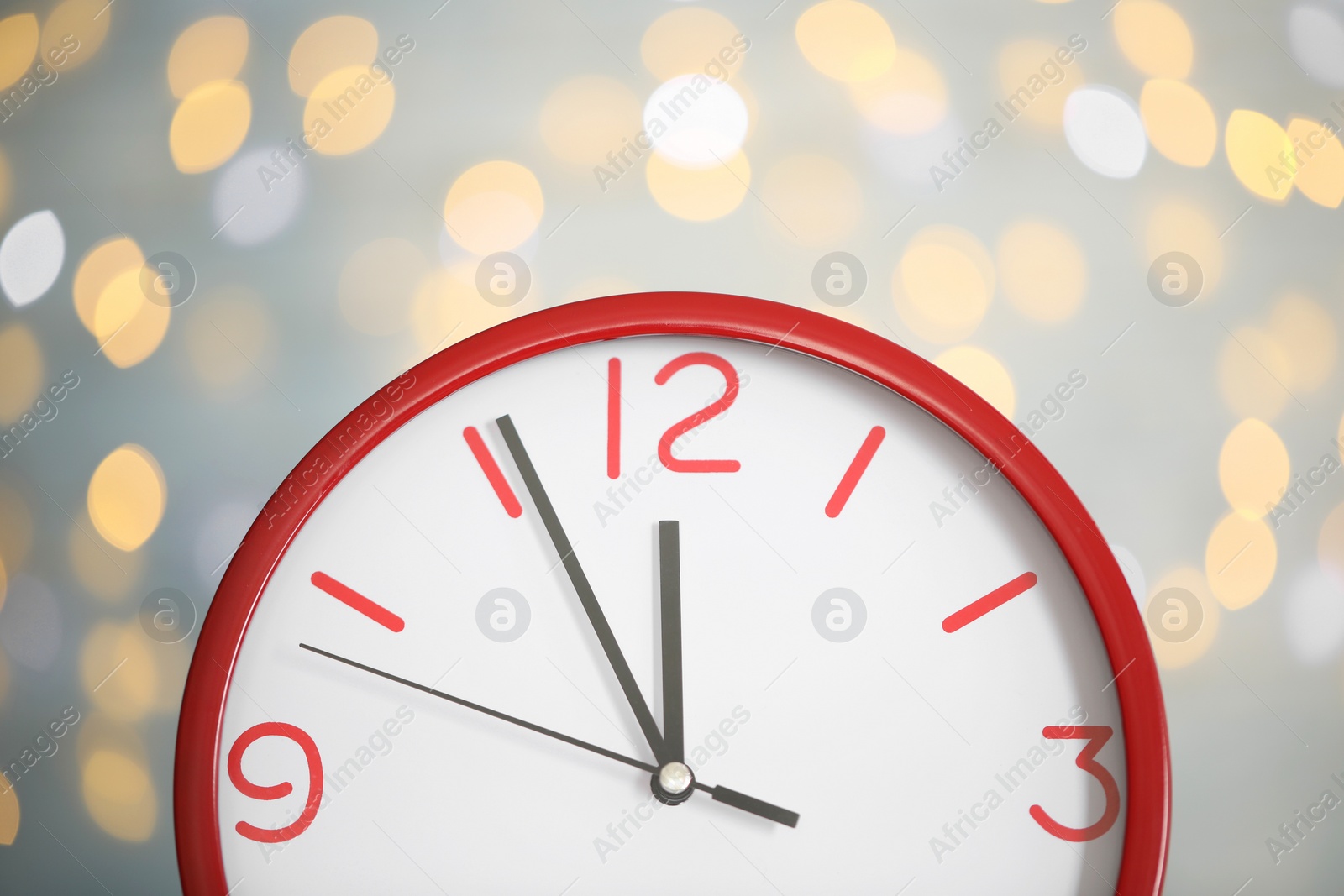 Photo of Clock showing five minutes until midnight on blurred background, closeup. New Year countdown