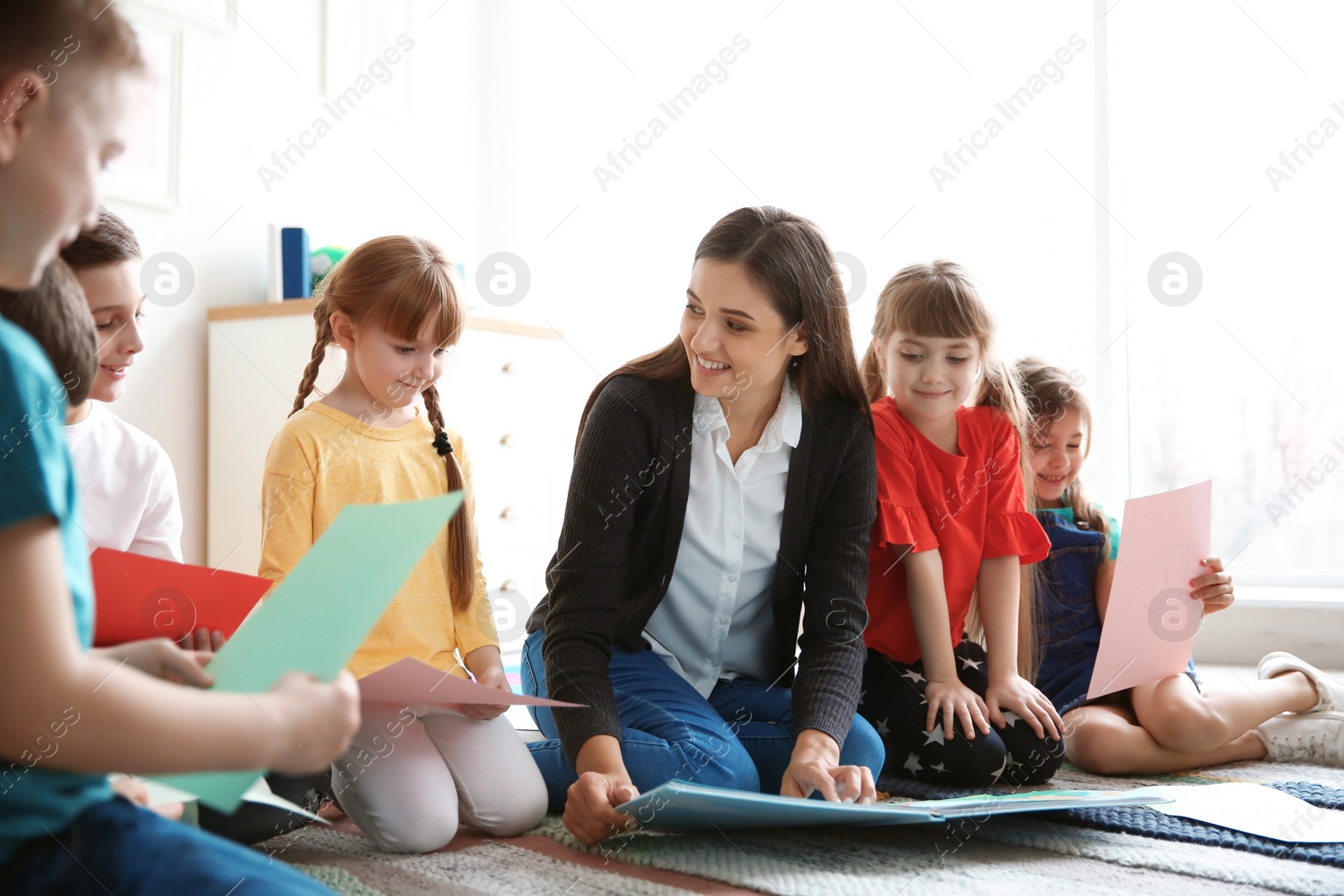 Photo of Cute little children with teacher in classroom at school