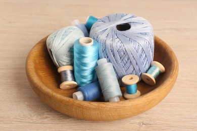Color sewing threads in bowl on wooden table