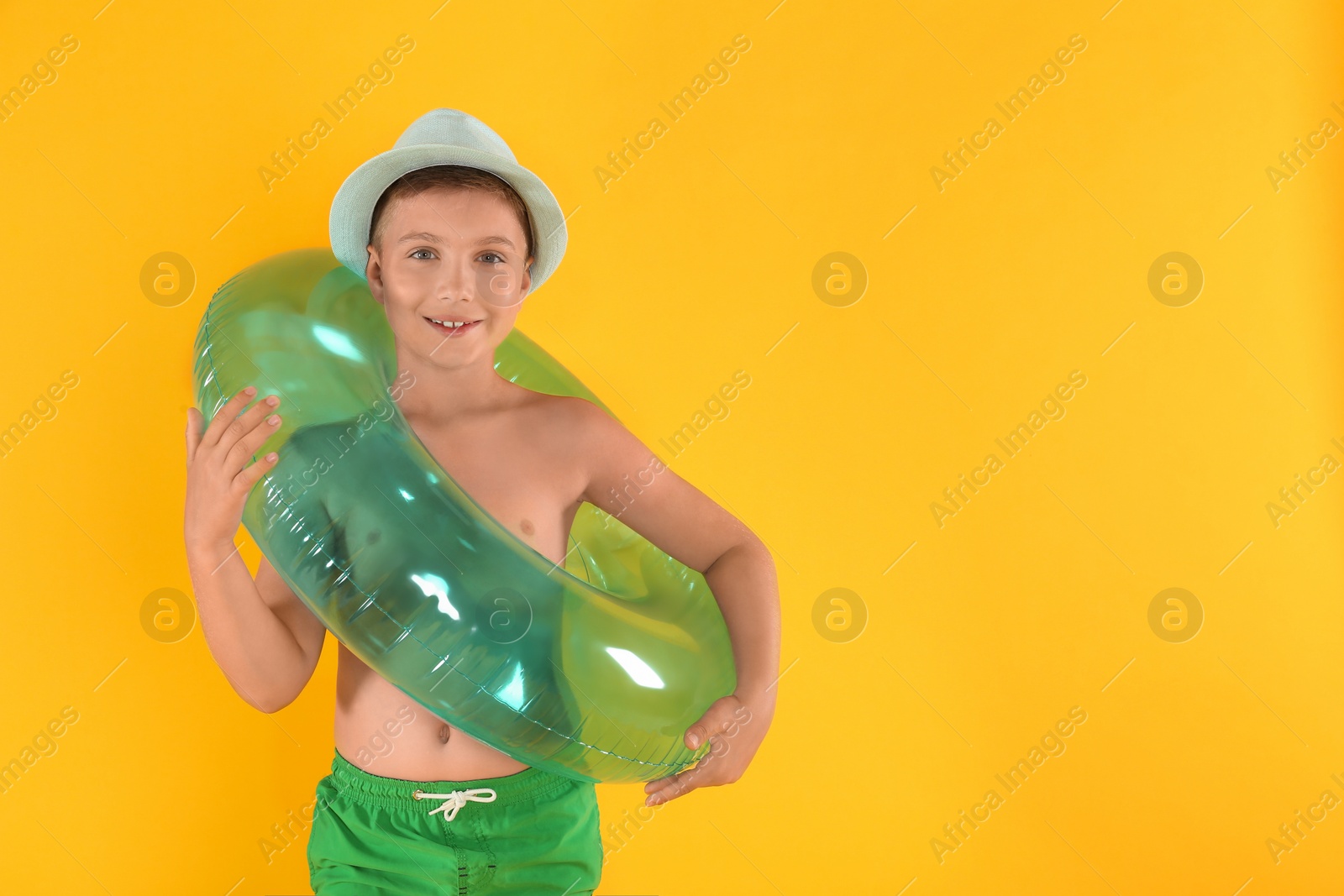 Photo of Cute little child in beachwear with bright inflatable ring on yellow background. Space for text