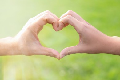Photo of Couple making heart with hands outdoors, closeup