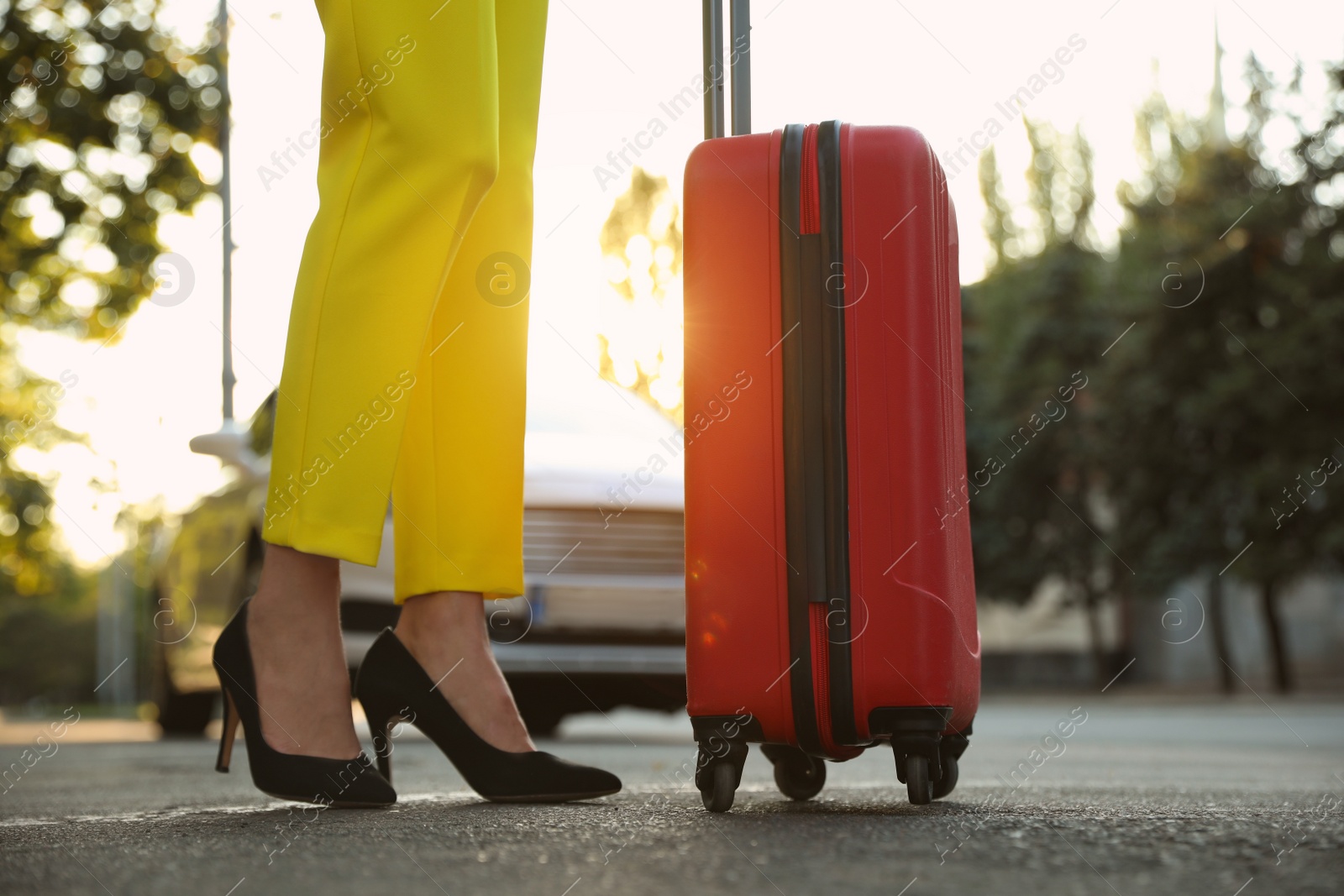 Photo of Woman with suitcase waiting for taxi on city street, closeup