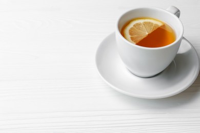 Cup with delicious immunity boosting tea and lemon on white wooden table, space for text