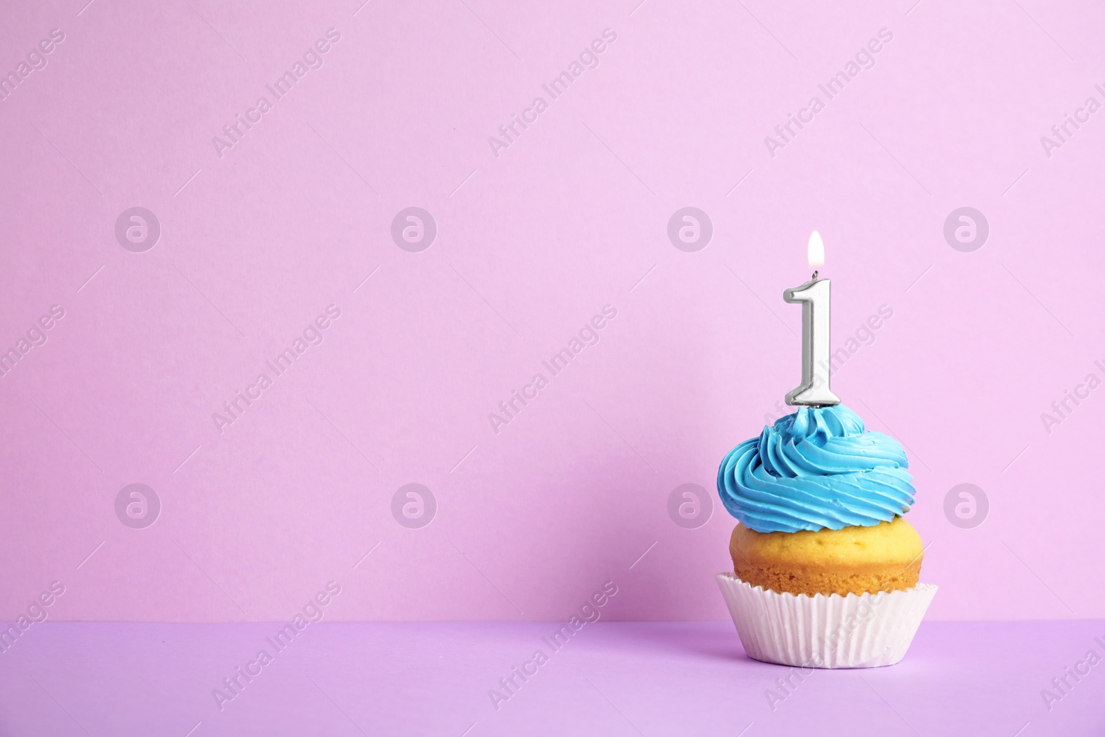 Photo of Birthday cupcake with number one candle on violet background, space for text