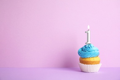 Photo of Birthday cupcake with number one candle on violet background, space for text