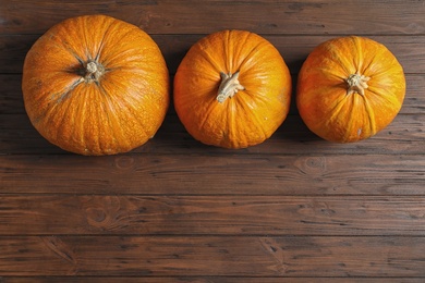 Photo of Flat lay composition with pumpkins and space for text on wooden background. Autumn holidays