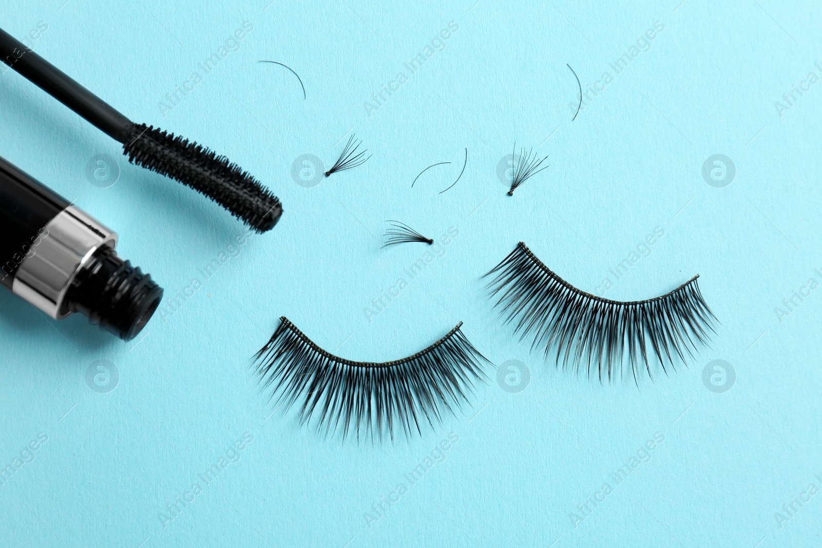 Photo of Mascara and false eyelashes on color background, top view