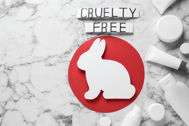 Flat lay of cards with phrase Cruelty Free, rabbit figure and personal care products on white marble table. Stop animal tests