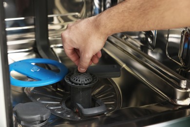 Photo of Repairman pulling drain filter out of dishwasher, closeup