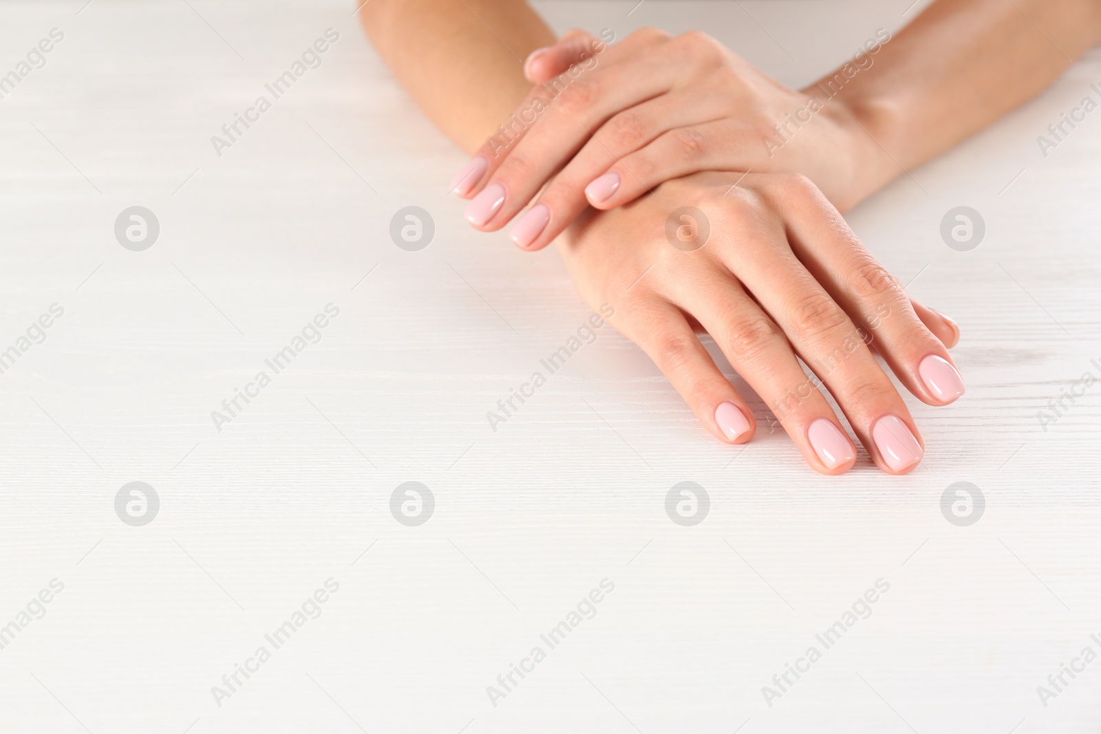 Photo of Closeup view of woman with beautiful hands at white wooden table, space for text. Spa treatment