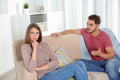 Photo of Young couple arguing in living room. Relationship problems