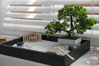 Photo of Beautiful miniature zen garden and candles on window sill