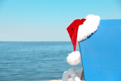 Photo of Lounge chair and Authentic Santa Claus hat on beach