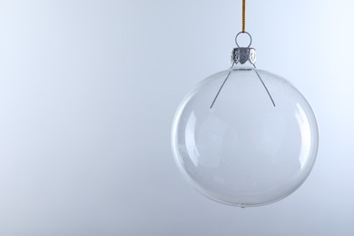 Photo of Transparent glass Christmas ball against light background. Space for text