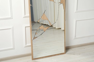 Photo of Broken mirror with many cracks near white wall indoors