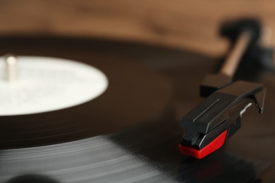 Vinyl record on turntable against blurred background, closeup