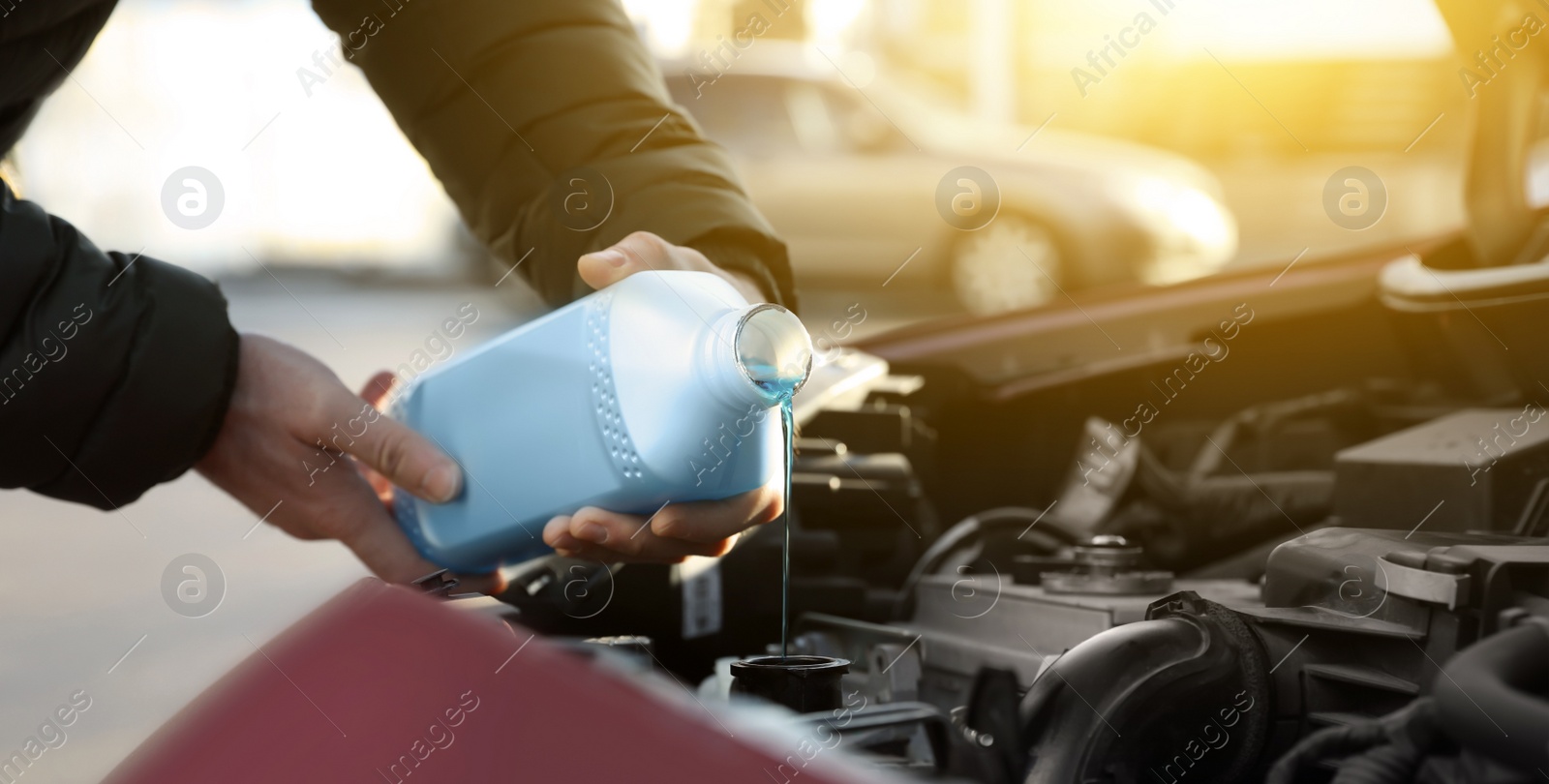 Image of Man filling car radiator with antifreeze outdoors, closeup