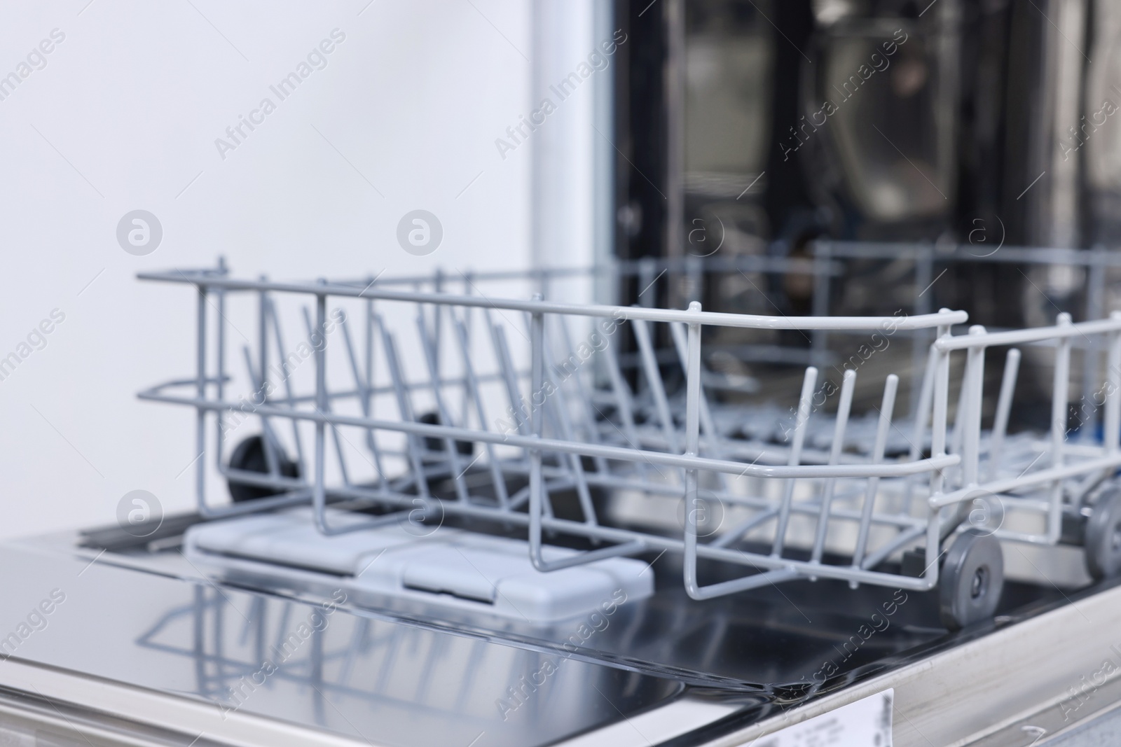 Photo of Open clean empty dishwasher indoors, closeup. Home appliance