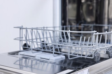 Photo of Open clean empty dishwasher indoors, closeup. Home appliance