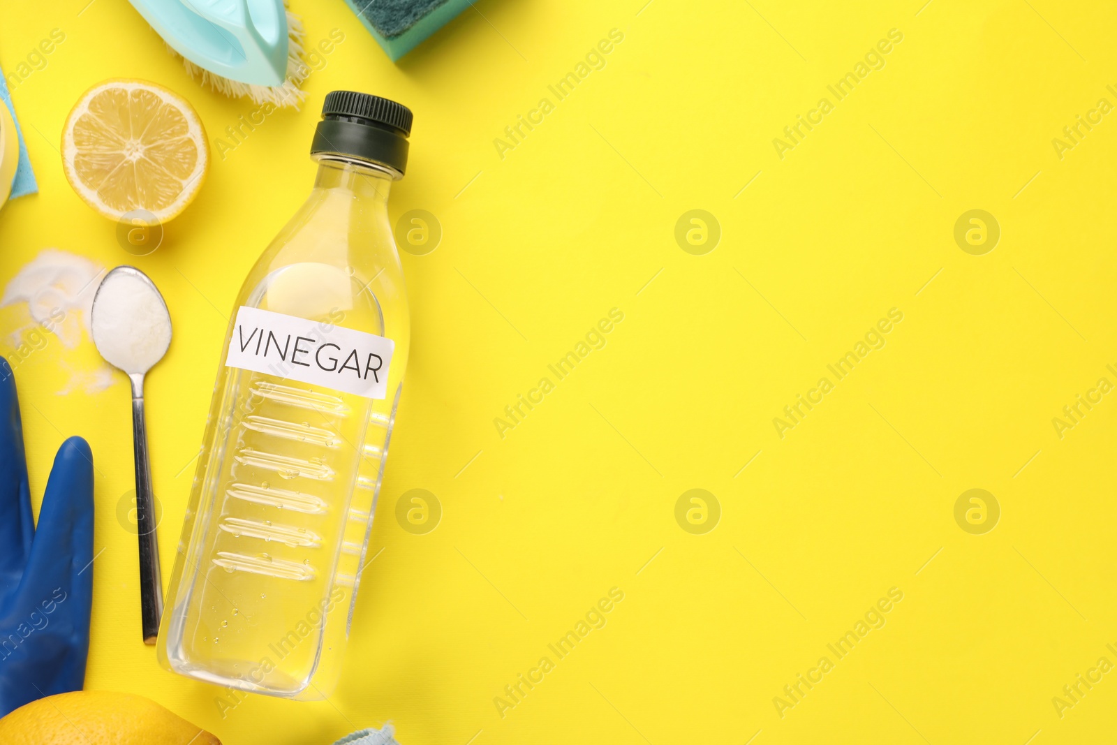 Photo of Eco friendly natural cleaners. Flat lay composition with bottle of vinegar on yellow background, space for text