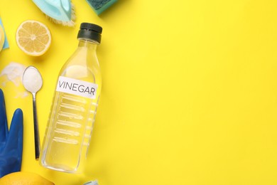 Photo of Eco friendly natural cleaners. Flat lay composition with bottle of vinegar on yellow background, space for text