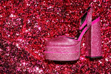 Photo of Fashionable punk square toe ankle strap pump on red sequins, top view with space for text. Shiny party platform high heeled shoe