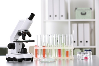 Photo of Laboratory glassware and microscope on table indoors. Research and analysis