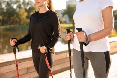 Photo of Women practicing Nordic walking with poles outdoors on sunny day, closeup