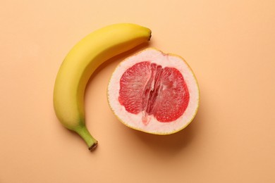 Photo of Banana and half of grapefruit on pale orange background, flat lay. Sex concept