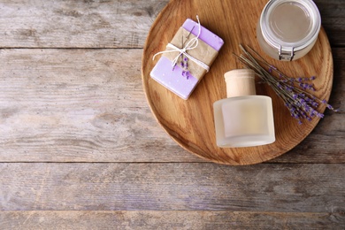 Photo of Flat lay composition with natural herbal oil, soap and lavender flowers on wooden background. Space for text