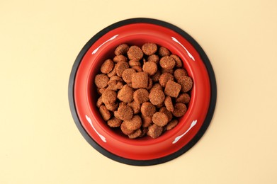 Photo of Dry dog food in feeding bowl on beige background, top view