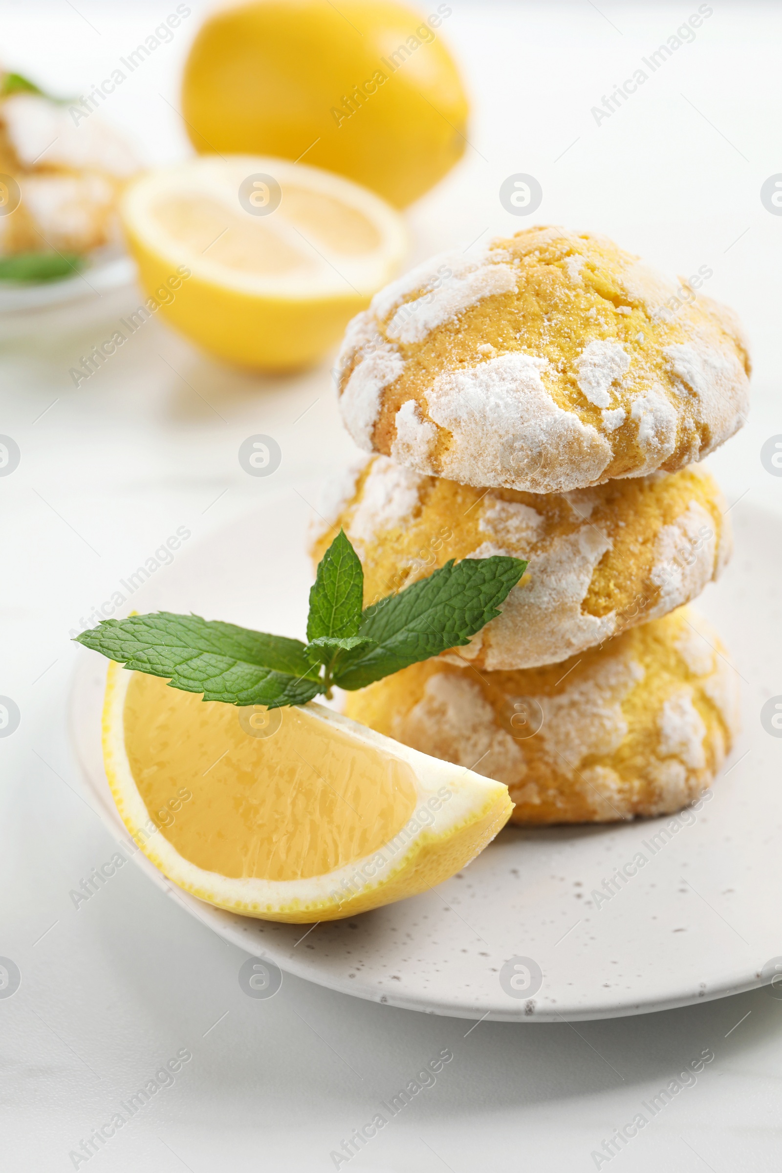 Photo of Tasty homemade lemon cookies with fresh fruit and mint on white marble table