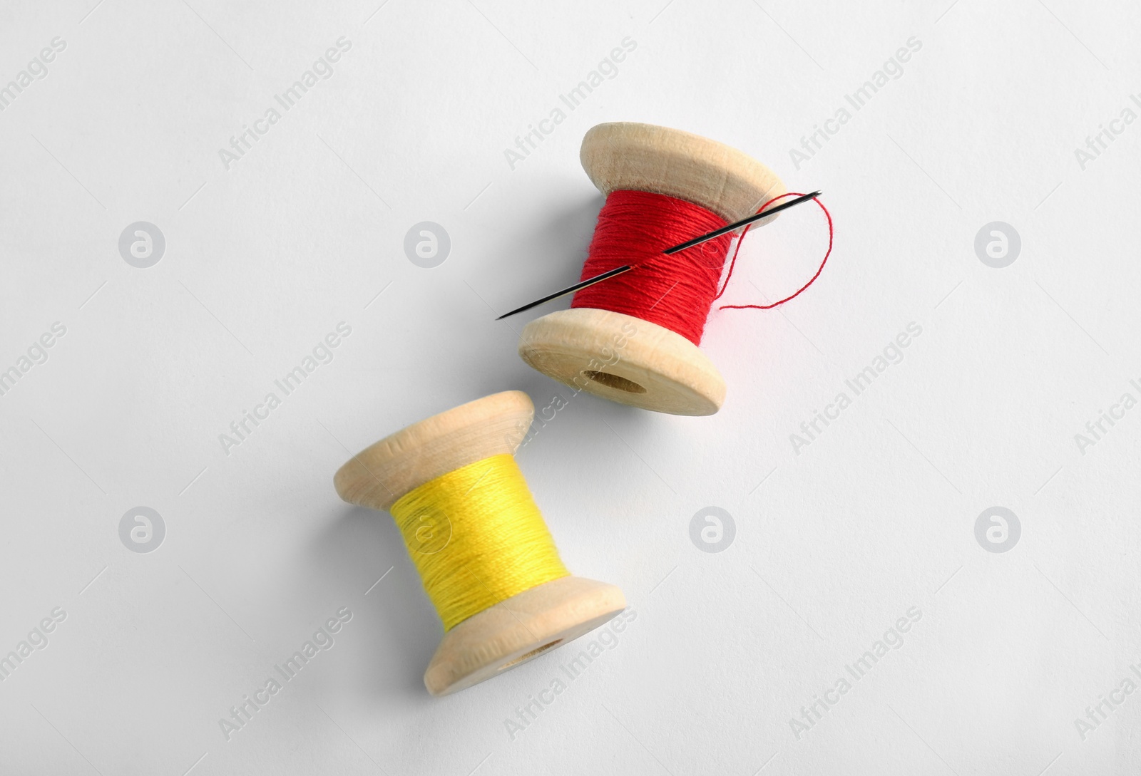 Photo of Colorful sewing threads with needle on white background, top view