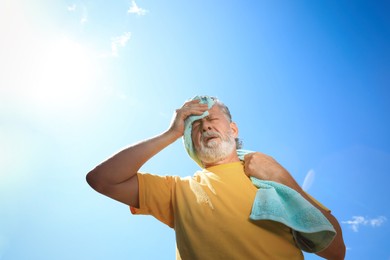 Photo of Senior man with towel suffering from heat stroke outdoors, low angle view