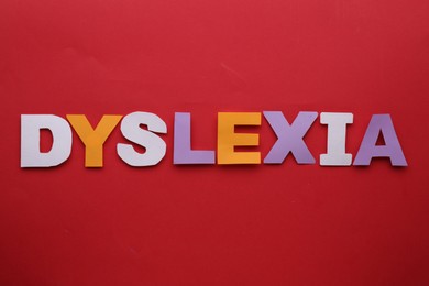 Photo of Word Dyslexia made of paper letters on red background, flat lay