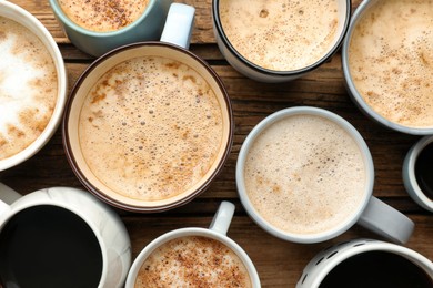 Photo of Many cups of different coffees on wooden table, flat lay