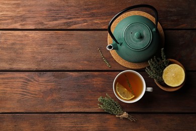 Photo of Aromatic herbal tea with thyme and lemon on wooden table, flat lay. Space for text