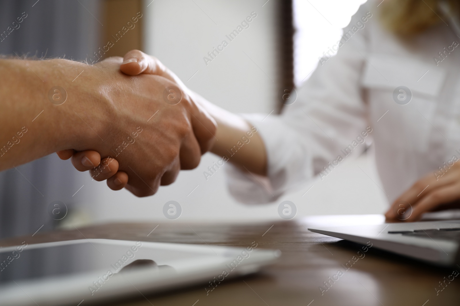 Photo of Business partners shaking hands at table after meeting in office, closeup