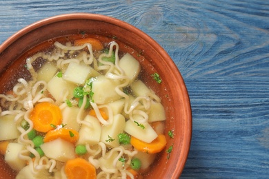 Photo of Bowl of fresh homemade vegetable soup on blue wooden background, top view. Space for text