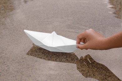 Photo of Kid launching small white paper boat on water outdoors, closeup