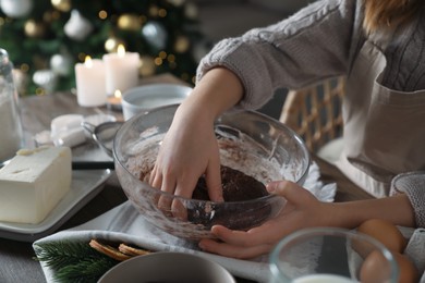 Photo of Little child making Christmas pastry at wooden table, closeup