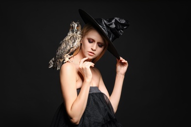 Witch in black hat with owl on dark background. Scary fantasy character