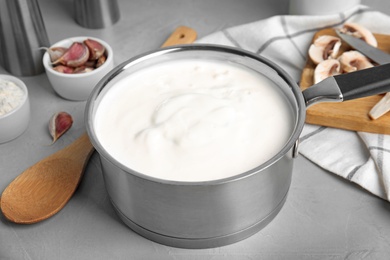 Photo of Delicious creamy sauce in pan on grey table