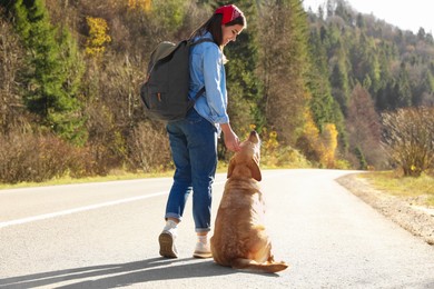 Happy woman and adorable dog on road. Traveling with pet