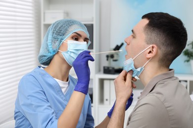 Laboratory testing. Doctor taking sample from patient's mouth with cotton swab in hospital