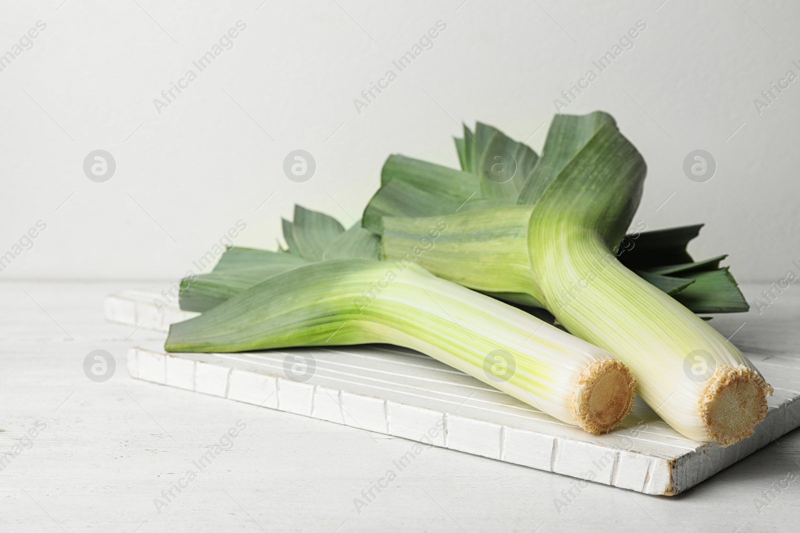 Photo of Fresh raw leeks on white wooden table. Ripe onion