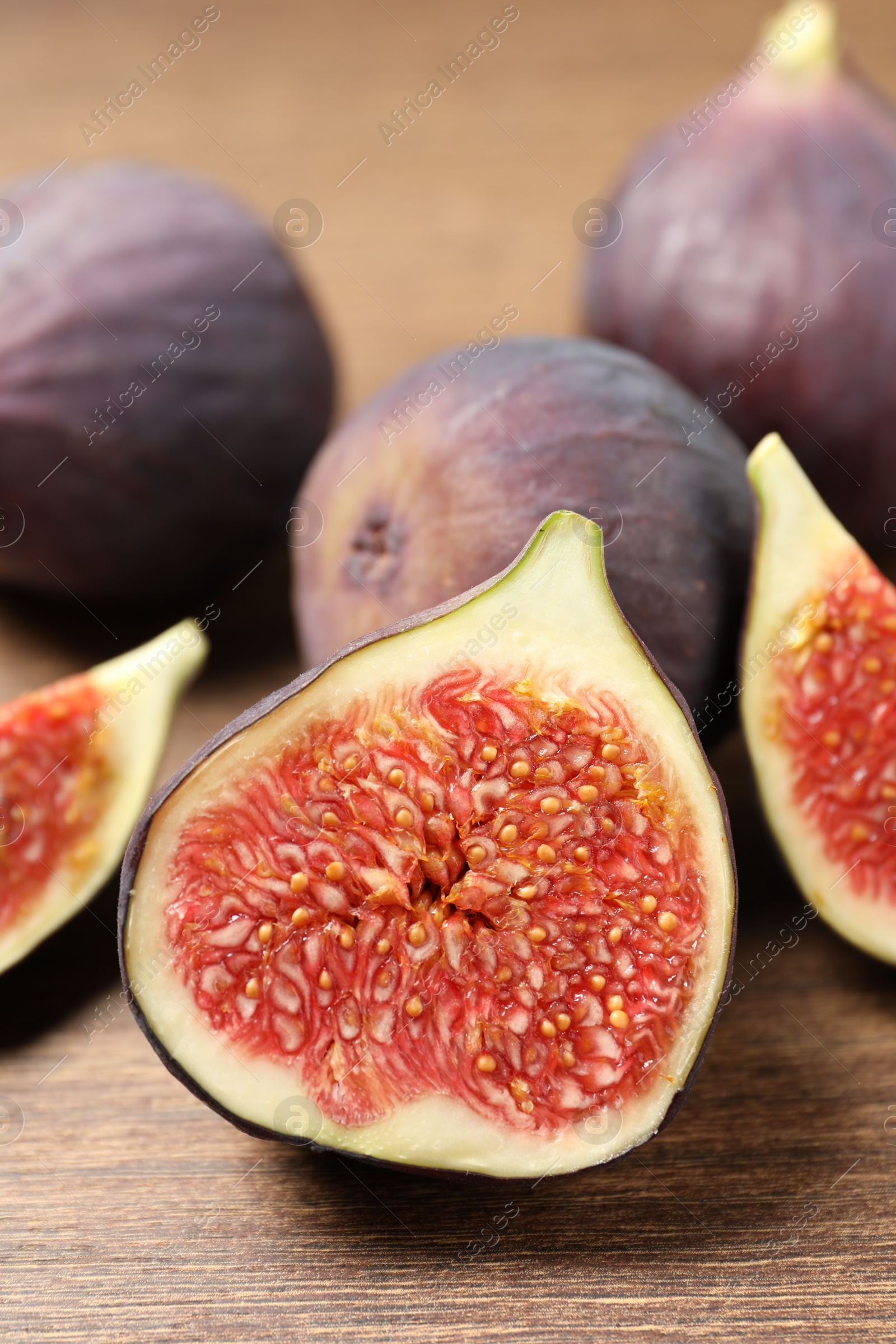 Photo of Whole and cut ripe figs on wooden table, closeup