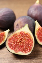 Whole and cut ripe figs on wooden table, closeup