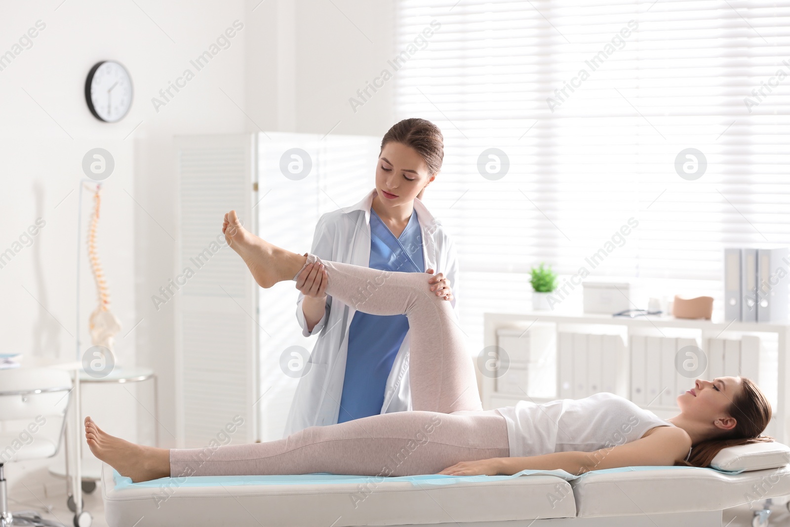 Photo of Female orthopedist examining patient's leg in clinic